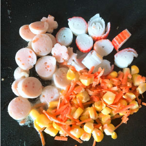 將明太子魚香腸、蟳味棒、玉米粒、紅蘿蔔絲,加入鹽、胡椒及3g番茄醬炒香備用