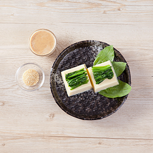 將芙蓉豆腐擺盤,放上燙熟的菠菜,淋上調好的胡麻醬汁,灑上白芝麻粒即完成