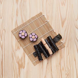 飯捏成棒狀放入海苔捲起,共五條;壽司棒中放入明太子魚香腸當花蕊後,以長條海苔包裹,最後用半張海苔將壽司包住並切開,再將備好的食材進行擺盤。