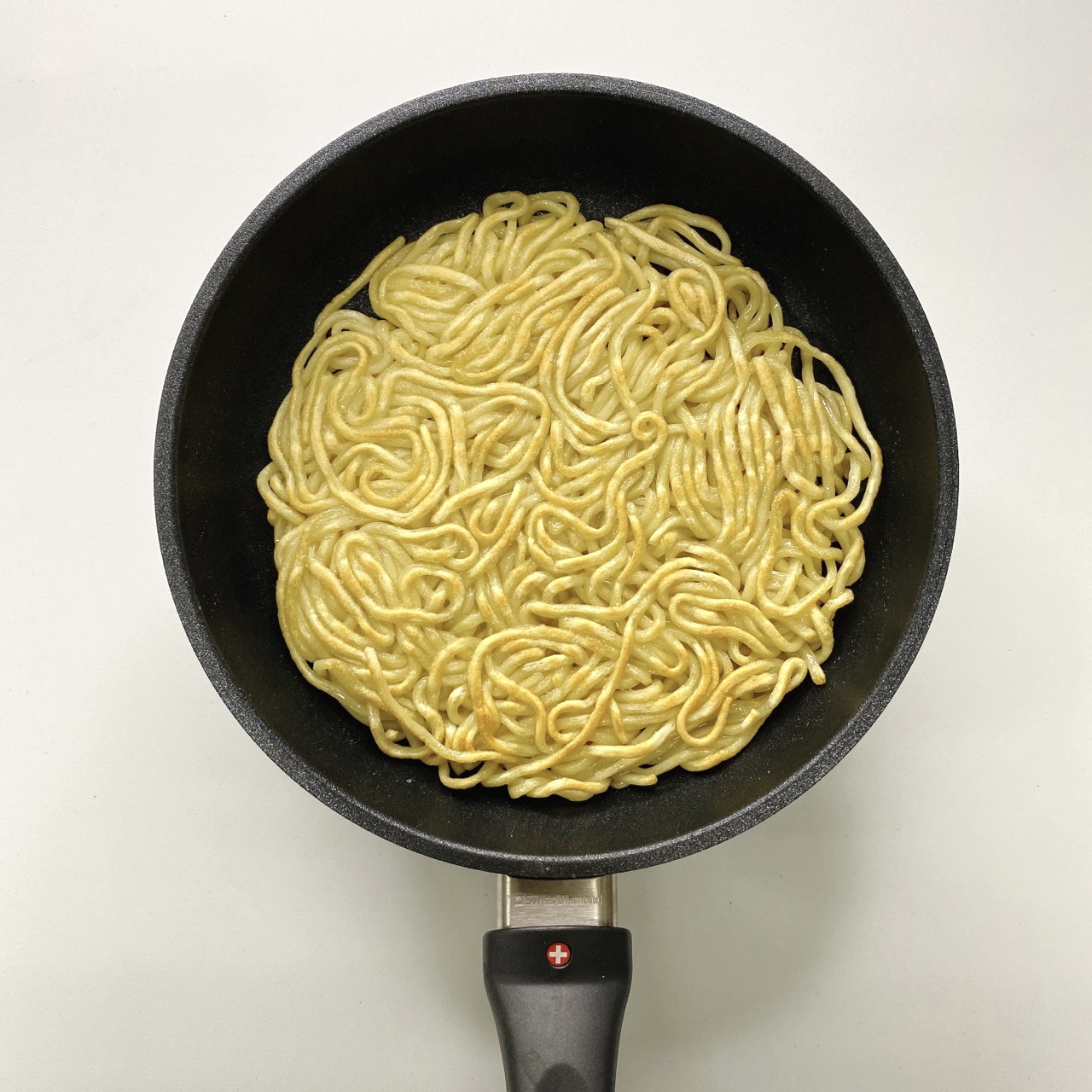 加一點點油在平底鍋,將油麵入鍋用小火煎,慢慢塑形,讓油麵聚集,一面定型後就可以翻面,把兩面都煎至焦黃就可以起鍋裝盤。