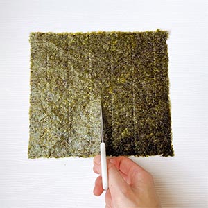 海苔片光滑面朝下,從底邊向中間剪開到一半