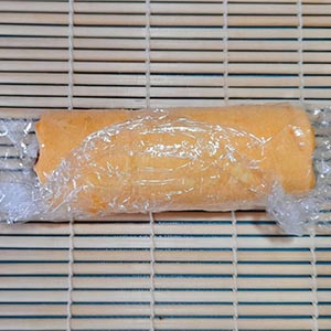 在壽司捲簾上鋪保鮮膜,放上蛋皮和一片海苔