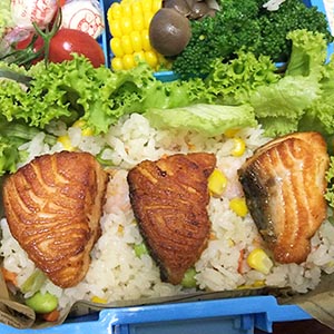 炒飯平鋪在便當盒,再將煎好的鮭魚放在炒飯上,最後每塊鮭魚片上都放一片小怪獸造型檸檬片。
