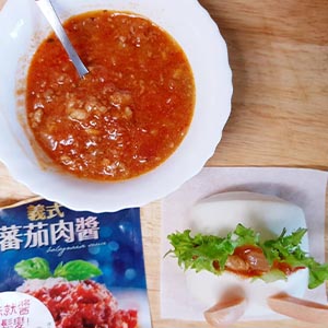 把生菜塞進饅頭上方的切痕裡,再舀入加熱好的義式蕃茄肉醬