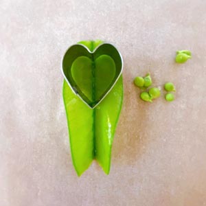 加熱鮭魚炒飯後,並鋪在便當盒底部
開始製作「小瓢蟲」!
(1.) 荷蘭豆去絲滾水燙一分鐘取出放涼
(2.) 從彎的那邊剪開,取出豆子,打開用愛心壓模,對準中心線壓出幸運草葉子
(沒有愛心壓模可以取出豆子以後,直接從相連的地方往外剪,打開變成愛心型)
