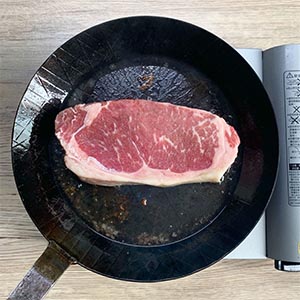 鍋內不放油放入修下的油脂，小火加熱煸出牛油後丟棄，接著將油燒熱放入紐約客牛排，單面煎上色(約1分鐘)後翻面，另一面略煎後，轉將側面煎上色，取出靜置5分鐘。