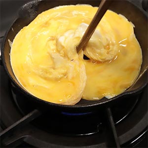加熱小鐵鍋後刷一層油、倒入蛋液,在週邊稍凝固時攪拌一下讓蛋液呈半熟。