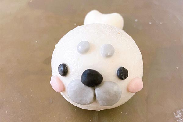 黑色湯圓糰做出眼睛和鼻子黏上，稍微按壓
水彩筆沾水在接縫處塗過一次，幫助密合完成，兩頰接縫處可以用牙籤再按壓
讓分線更清楚