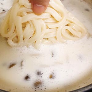 濃乳湯燒滾後加入鴻禧菇和內附冷凍烏龍麵再煮到湯滾。
