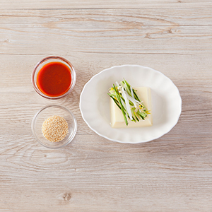 芙蓉豆腐放盤子上，依序放上豆芽菜、小黃瓜絲，淋上醬汁，再灑上白芝麻粒即完成
