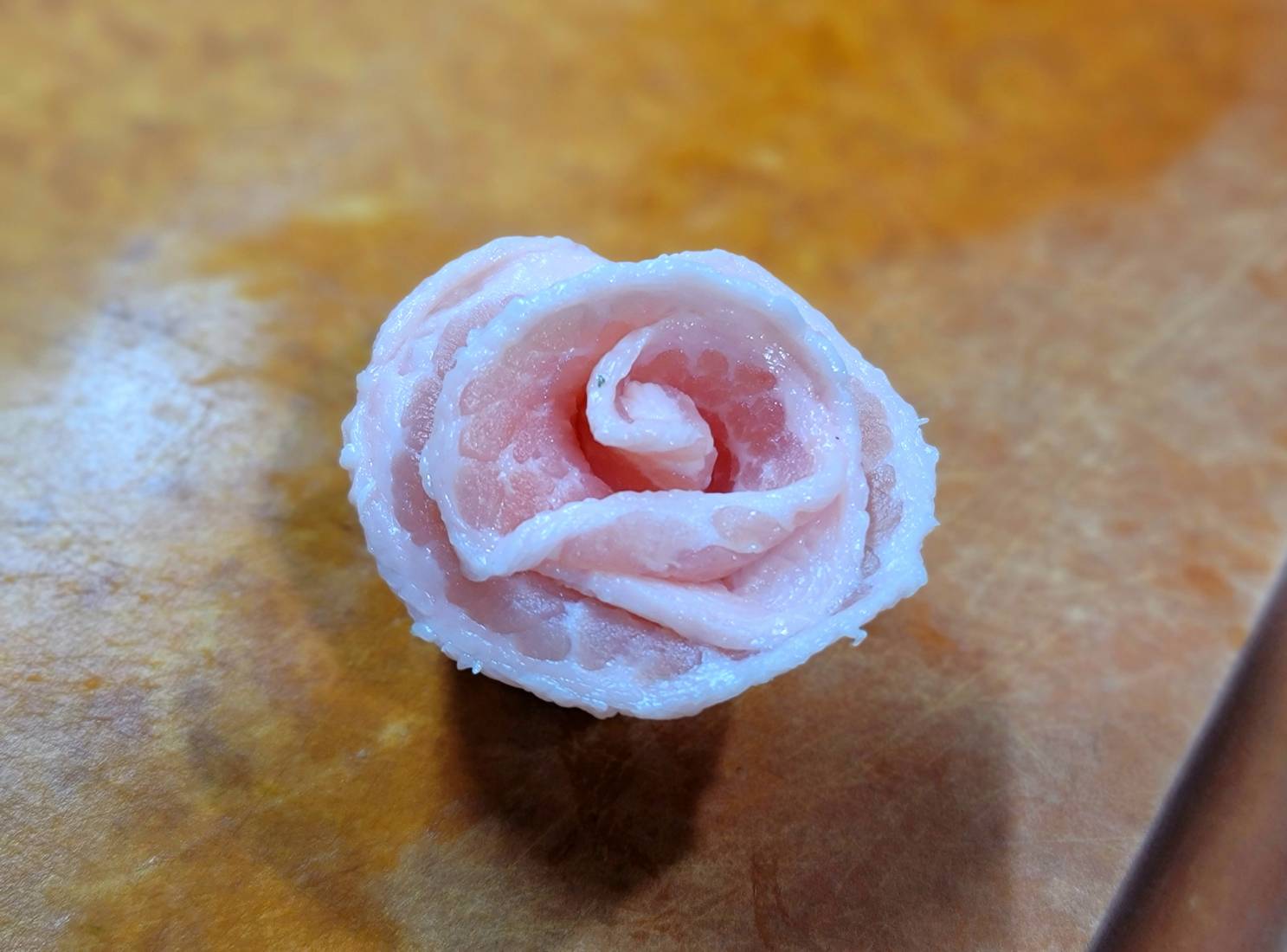 將兩片火鍋肉片接在一起呈長條,從一端捲到另一端,捲起後直放,將肉片稍微往外翻成花朵狀。