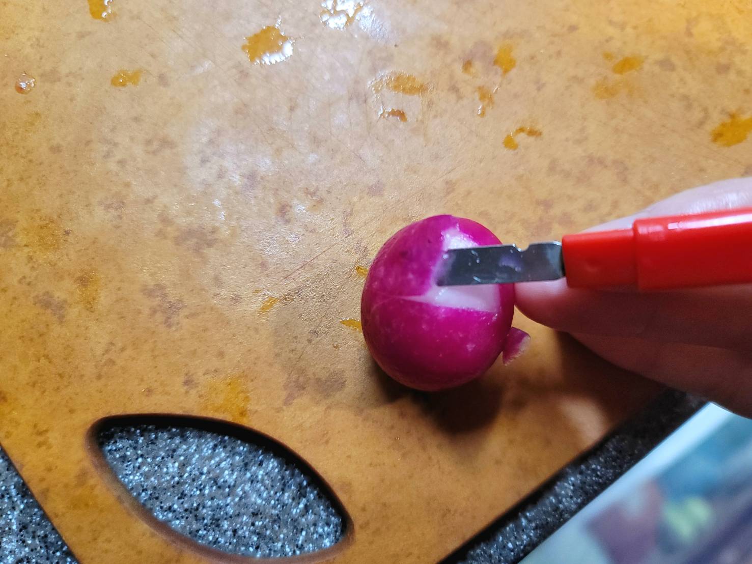 用食物雕刻刀將櫻桃蘿蔔劃出半月形,將紅色皮削除,再用水果刀在霸越形下方切出三個直條紋。