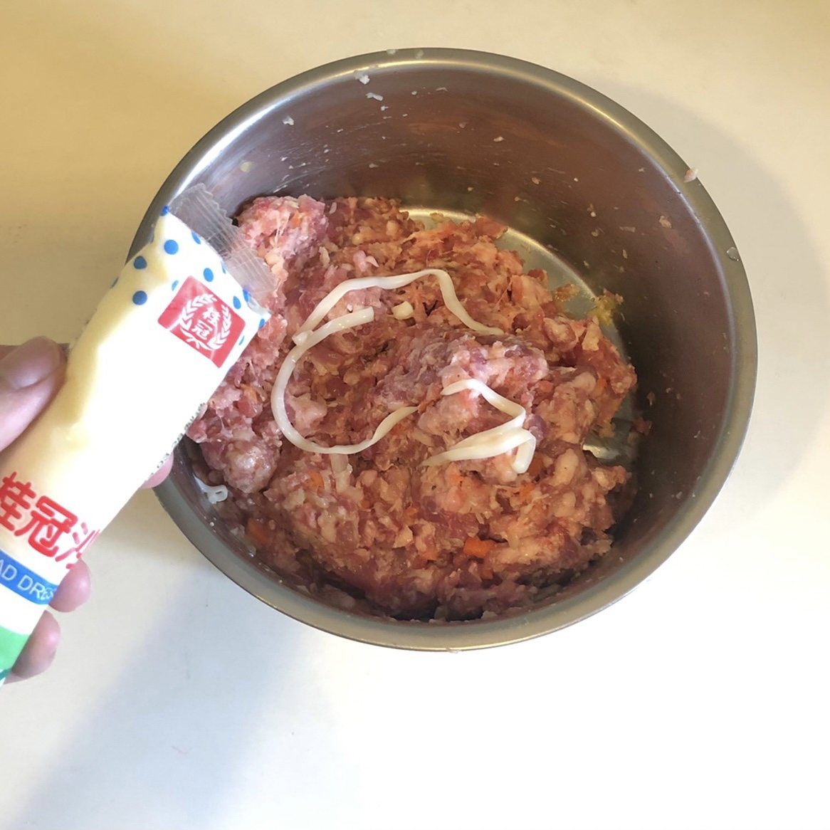 麵包粉加入一點鮮奶,調成微糊狀,並依序將絞肉、炒好的洋蔥和胡蘿蔔、調好的麵包粉以及一顆蛋,適量的鹽和黑胡椒攪拌均勻,再加入一點桂冠的沙拉醬,讓漢堡排更加順口。