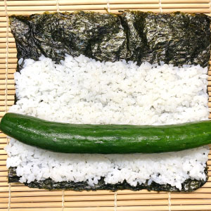 【四海壽司】海苔鋪平醋飯,放入一條小黃瓜捲起來。