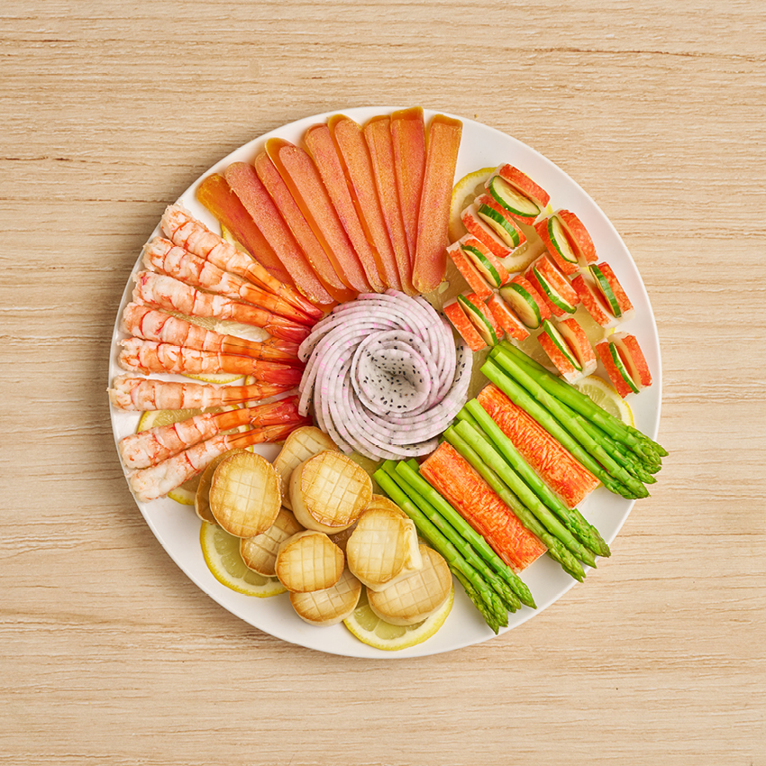 檸檬片鋪底,中間可將水果切片擺成花。其餘食材依序組裝,成為豐盛的海鮮拼盤。