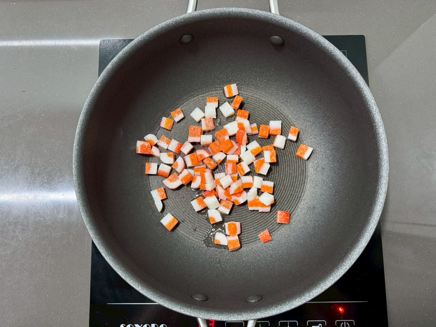 平底鍋加熱後,加入食用油。
放入切塊火鍋料,以中小火先加熱約1分鐘。
